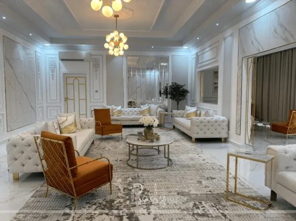 A stylish living room featuring white furniture and gold accents, designed by Rady Interior.