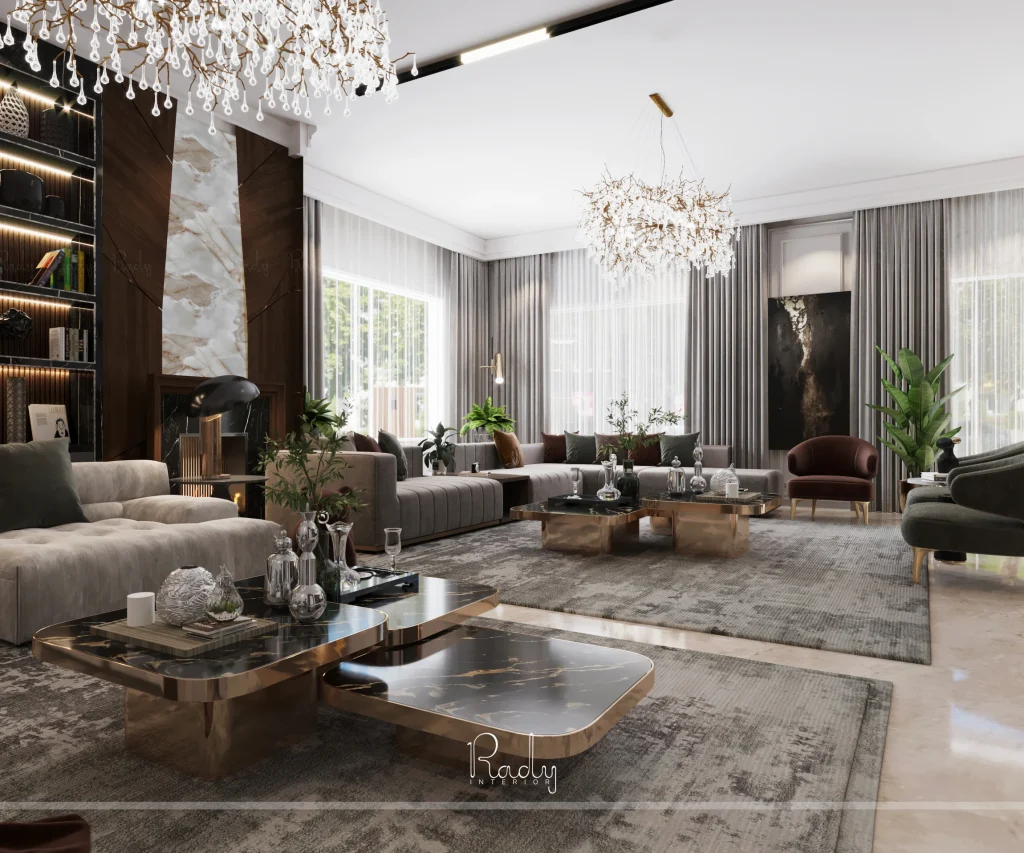 Spacious modern living room with two large gray sofas, marble coffee tables, chandeliers, and floor-to-ceiling windows with sheer curtains, featuring elegant neutral decor.