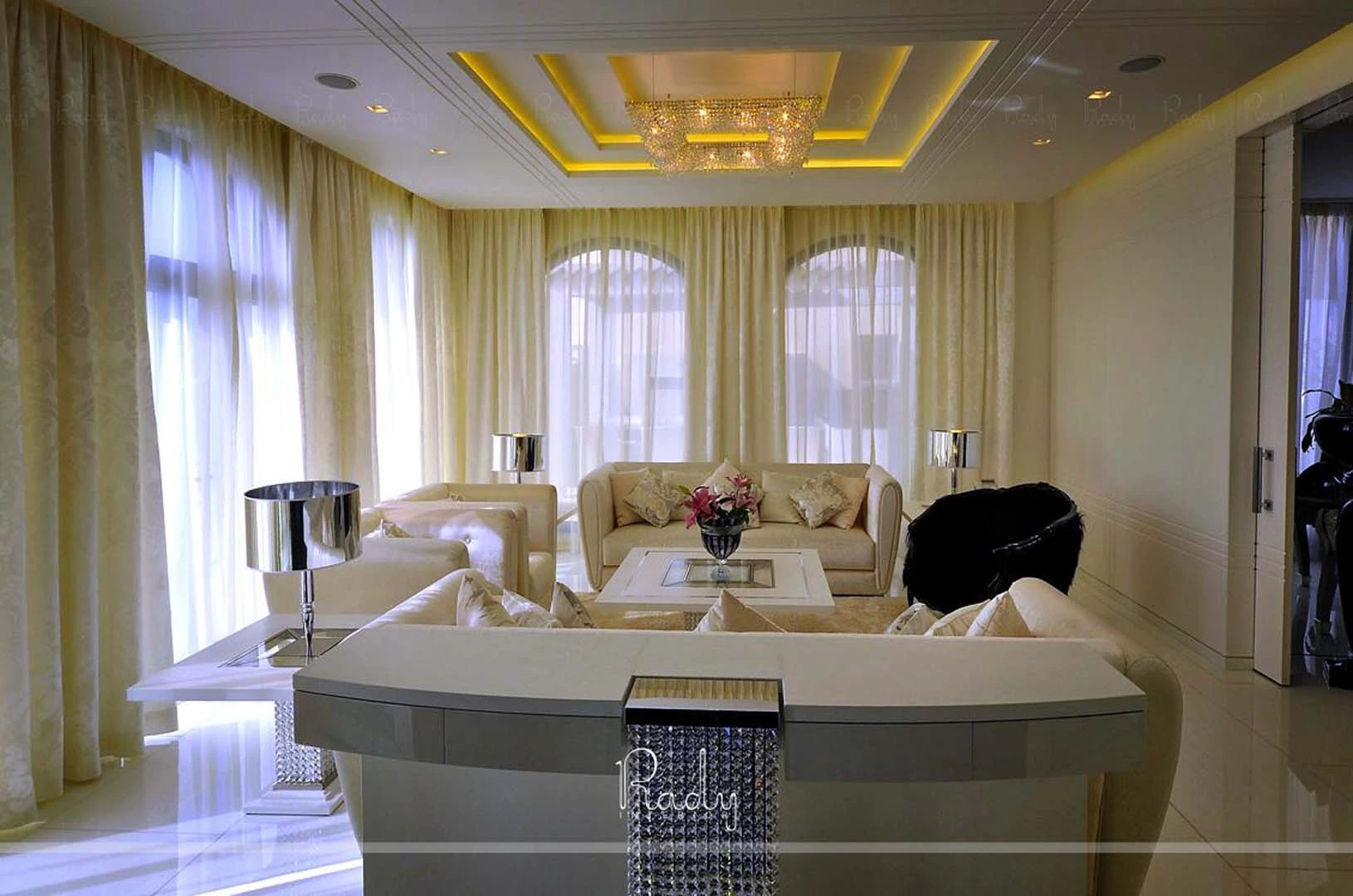A renovated villa living room in Palm Jumeirah featuring white furniture and an elegant chandelier.