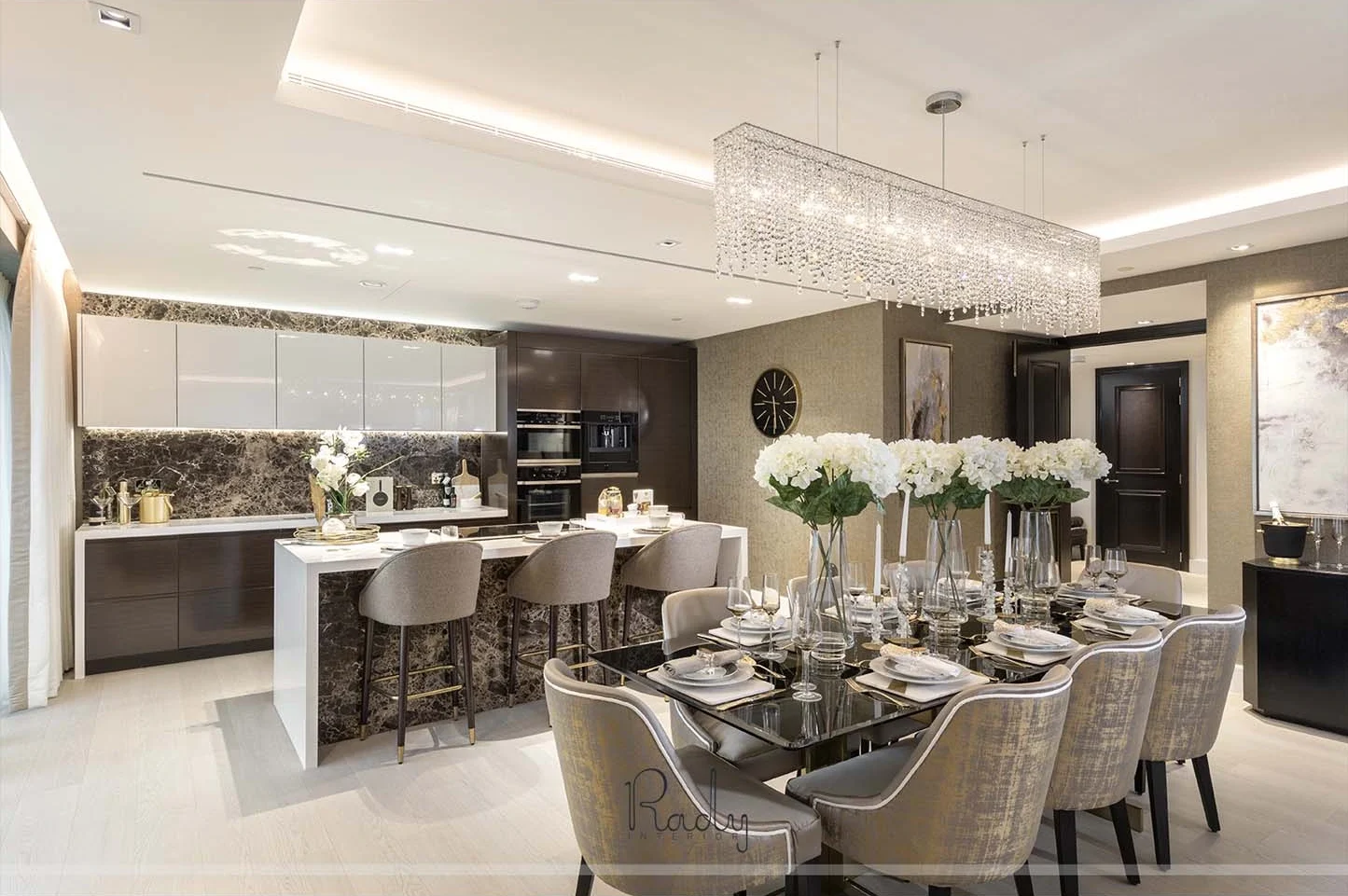 Modern kitchen and dining area featuring a stylish chandelier, part of a villa renovation in Palm Jumeirah by Rady Interior.